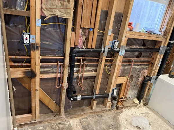Exposed framing, plumbing, and electrical boxes during a bathroom remodel.
