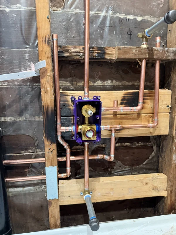 Copper pipework and the shower valve visible before the wall is closed.