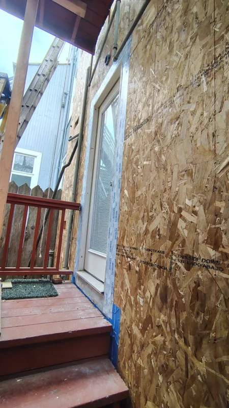 Wall sheathing in place around an exterior window and landing.