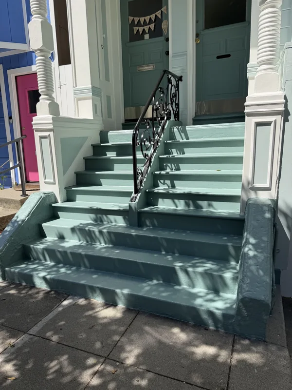 Green-painted entry steps, white trim, and dark metal railings.
