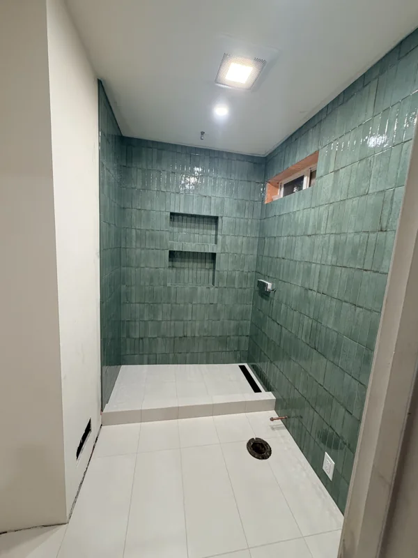 Wall tile, niches, and a shower base during installation, before the final fixtures.