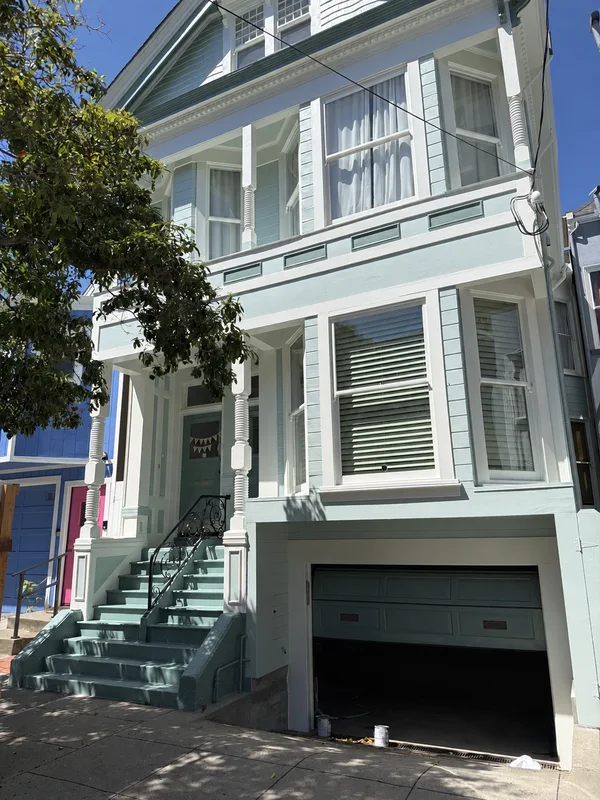 A soft green exterior and contrasting white trim bring the architectural details into focus.