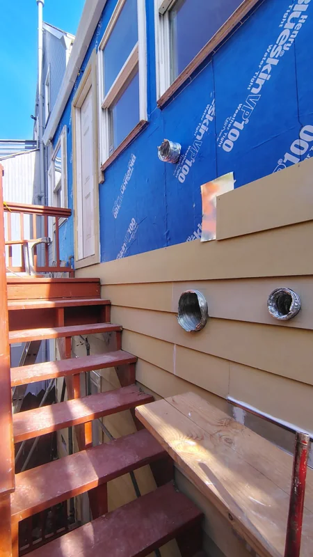 Siding installation underway beside the exterior stairway.