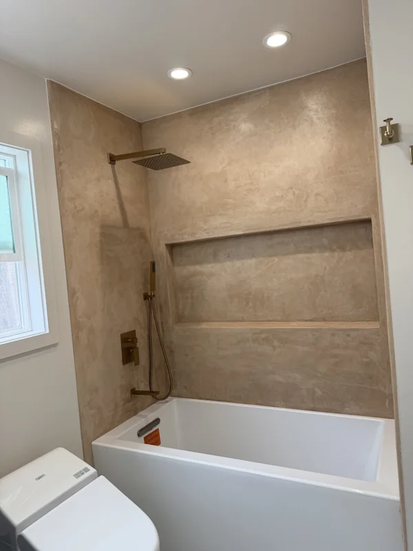 A recessed niche, stone-look tile, and coordinated tub and shower fixtures.