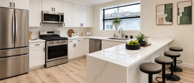White cabinetry, a waterfall peninsula, and warm wood-look flooring.